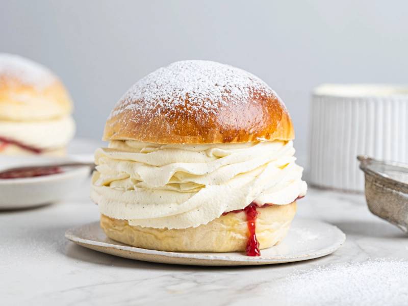 En fastelavnsbolle fylt med krem og syltetøy, pyntet med melis på toppen.