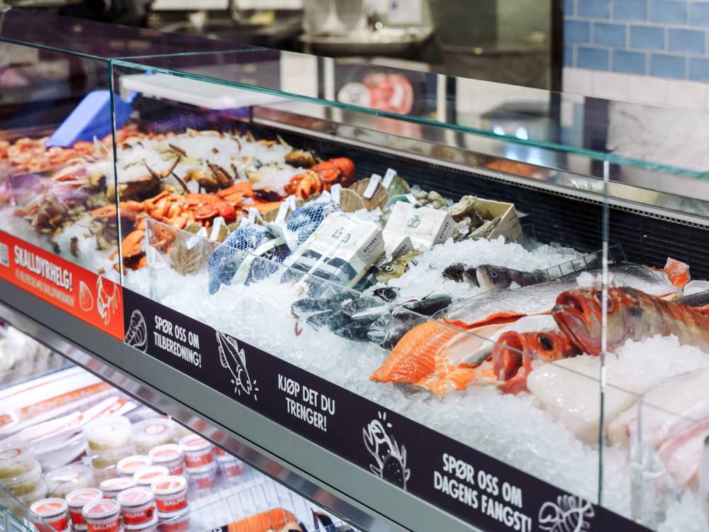 Fersk sjømat i en fiskedisk på MENY Frogner, med ulike typer fisk og skalldyr på isen.
