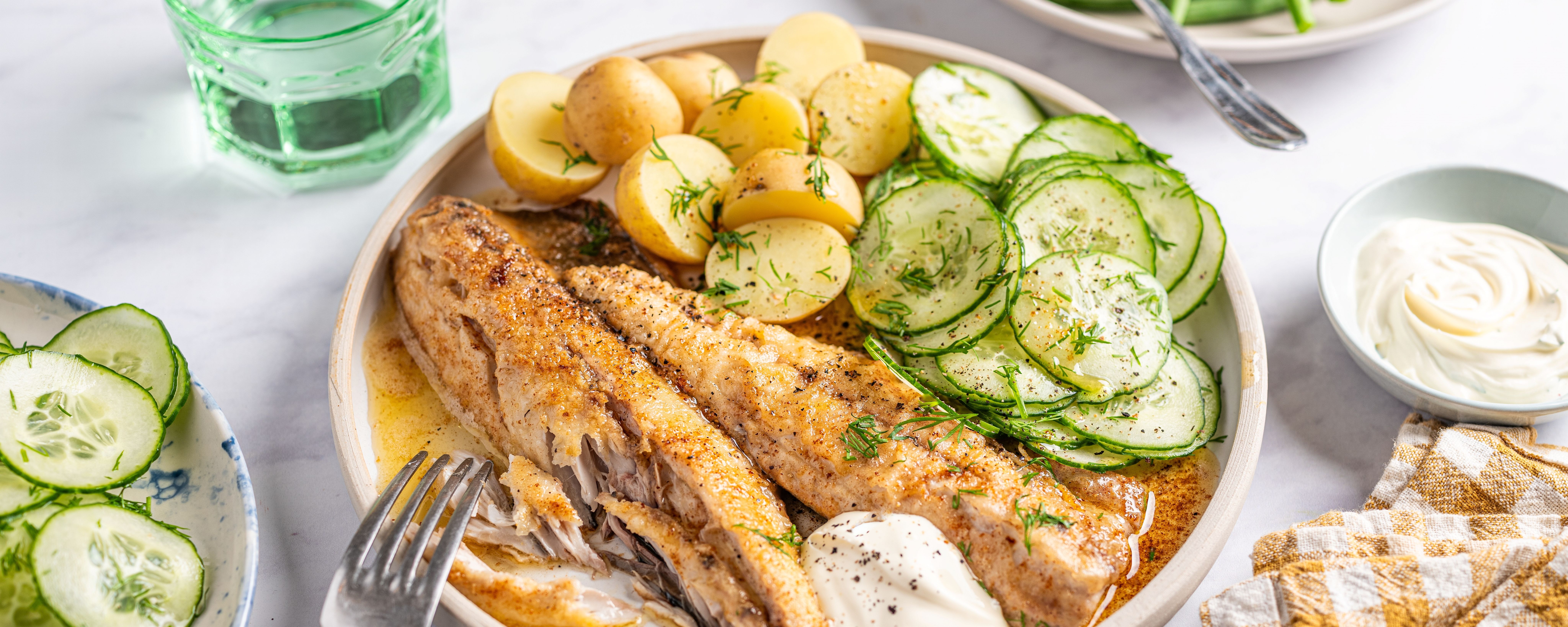 Stekt makrell med agurksalat og poteter på en tallerken.