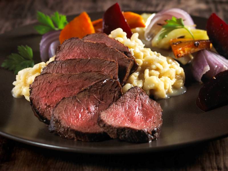 Hjortefilet med risotto og grønnsaker på en tallerken