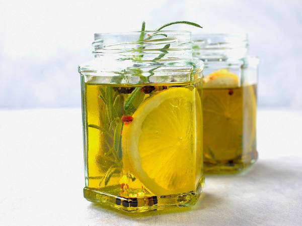 To glasskrukker med sitron- og urter i olje, plassert på en hvit overflate.