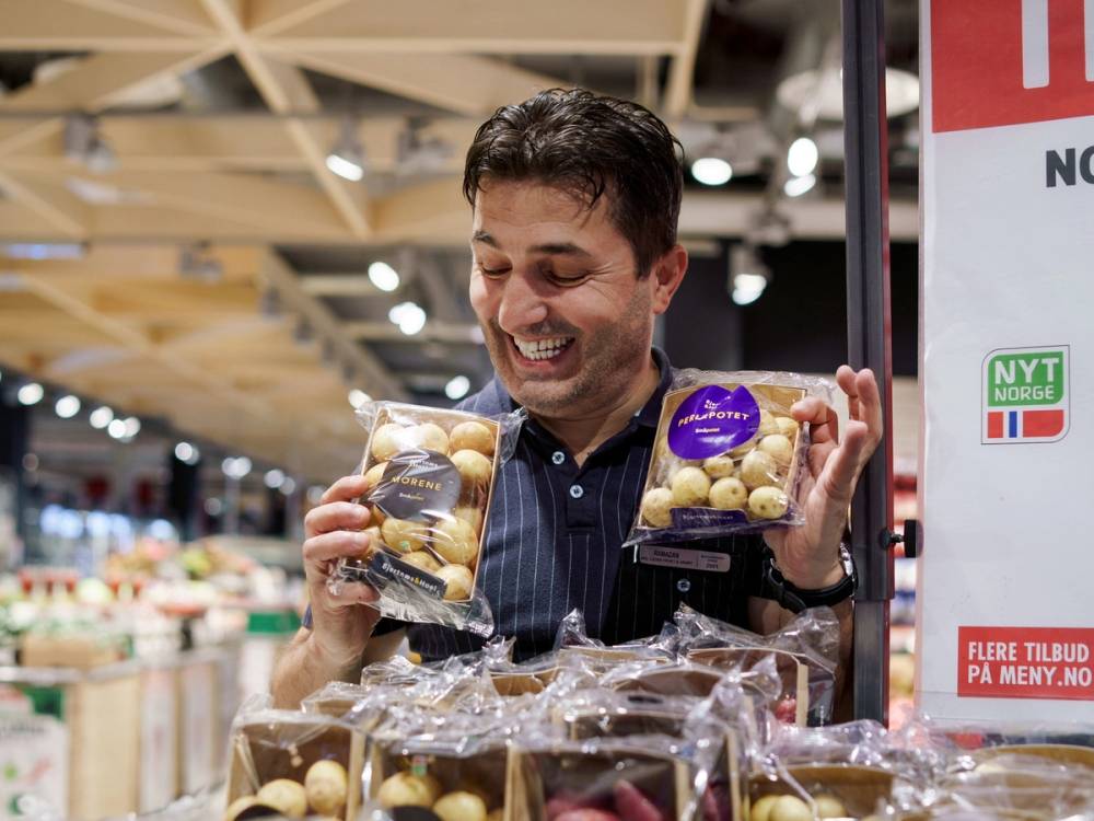 Person som holder to poser med sjokoladekuler i en matbutikk, med butikkhyller i bakgrunnen.