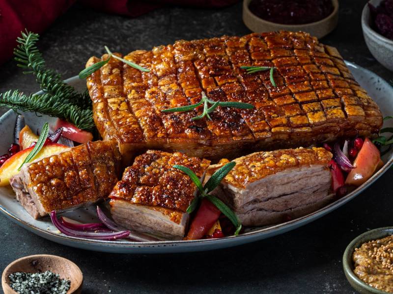 Stekt ribbe med sprø svor, servert med grønnsaker og tilbehør på en tallerken.
