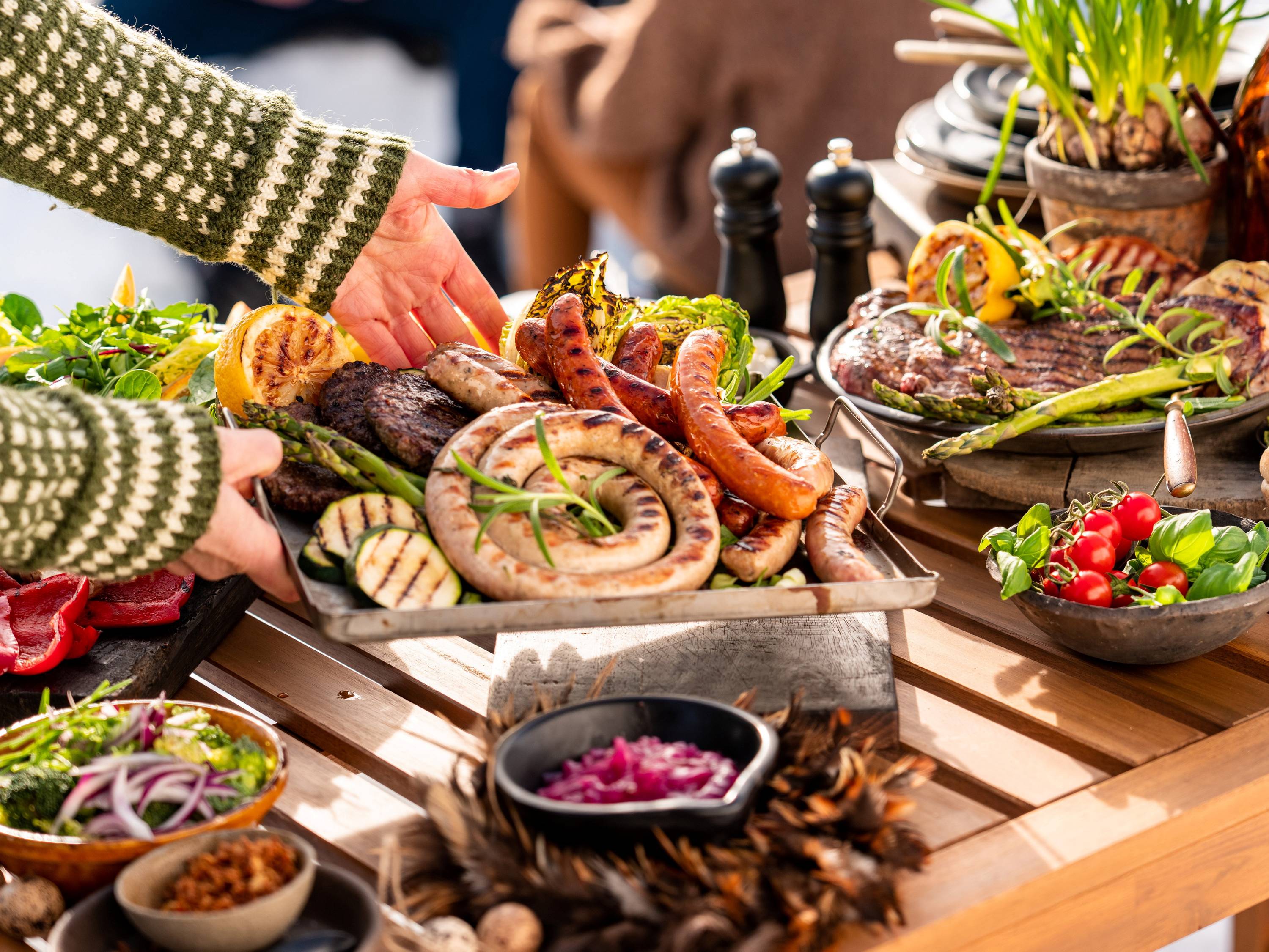Personer som deler et utvalg av sjømat og grønnsaker på et bord under en utendørs grilling eller fest.
