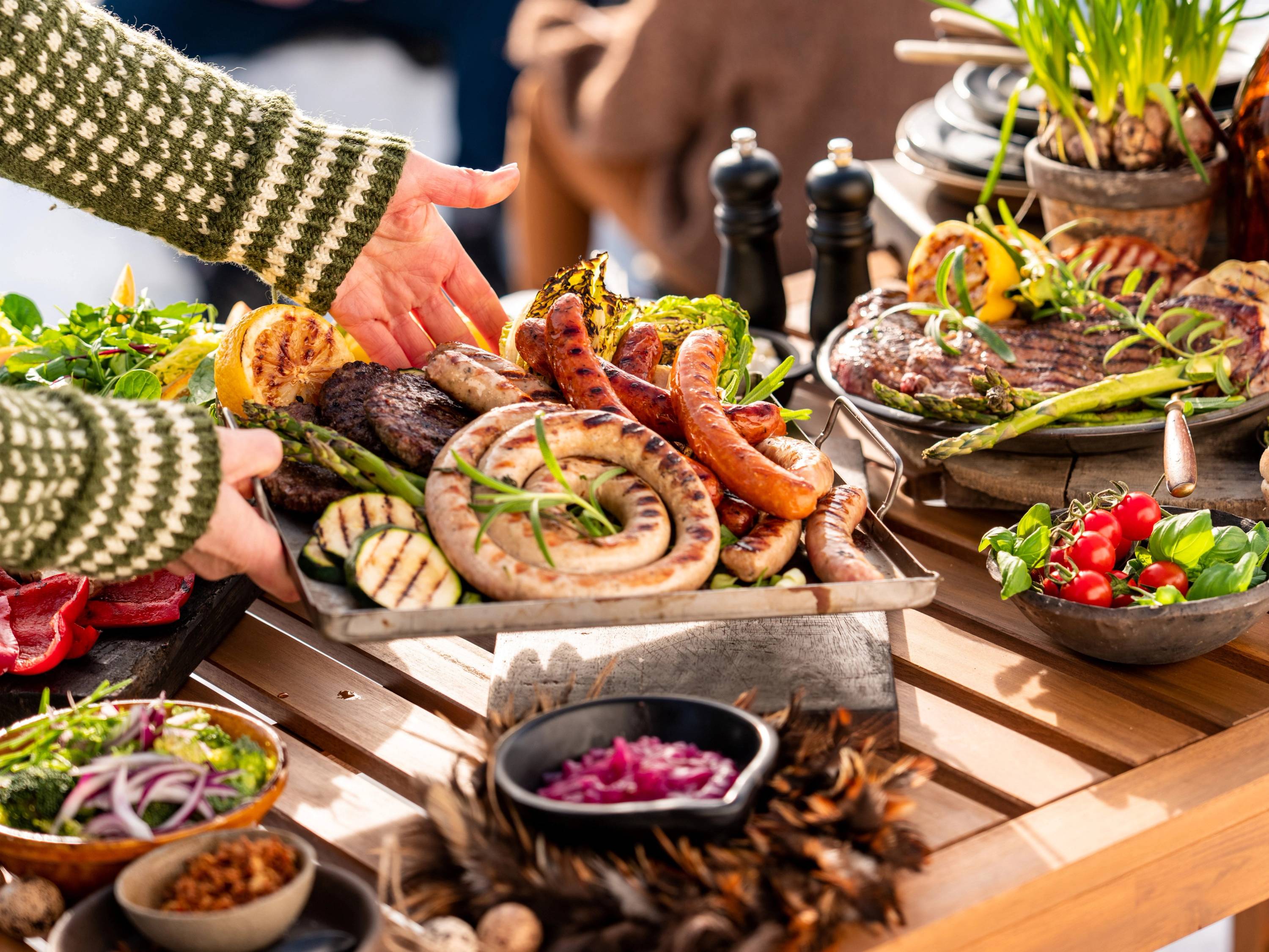 Personer som deler et utvalg av sjømat og grønnsaker på et bord under en utendørs grilling eller fest.