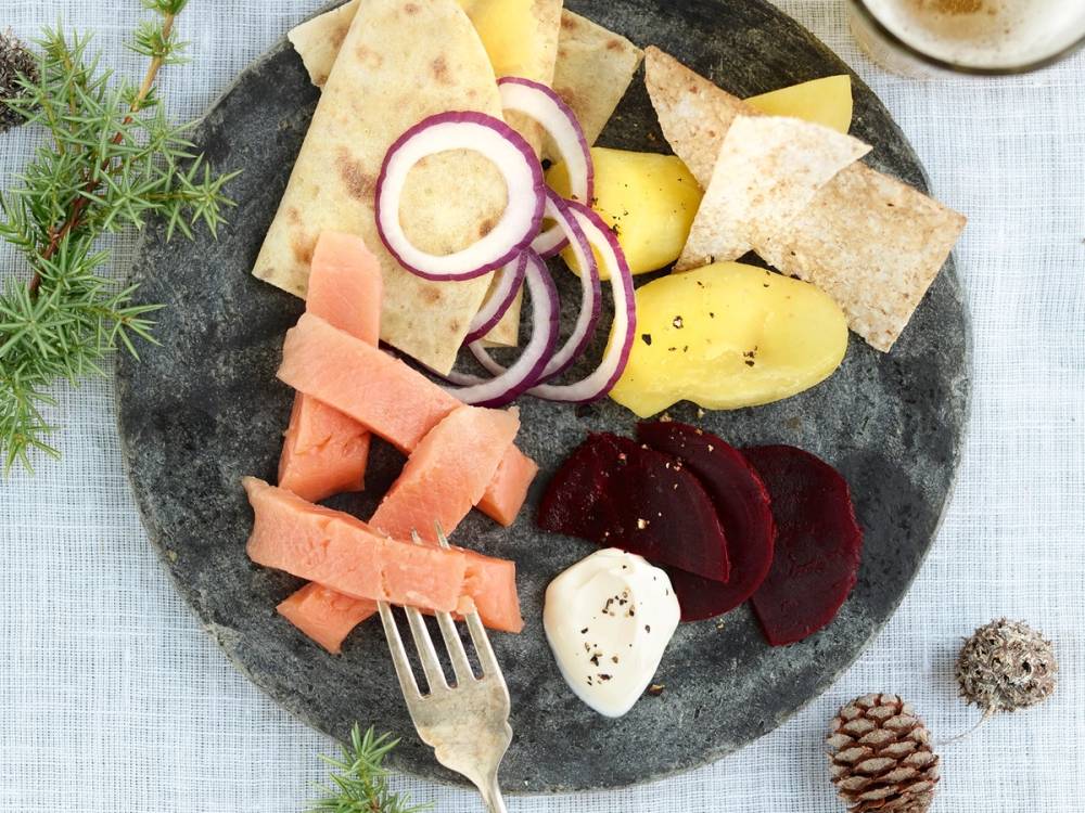 Rakfisktallerken med poteter, rødløk, og flatbrød på en svart tallerken.