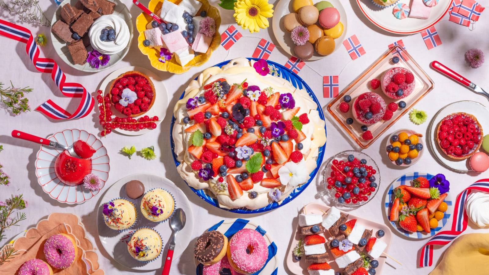 Dessertbord med pavlova, småkaker, desserter og norske flagg til 17. mai.