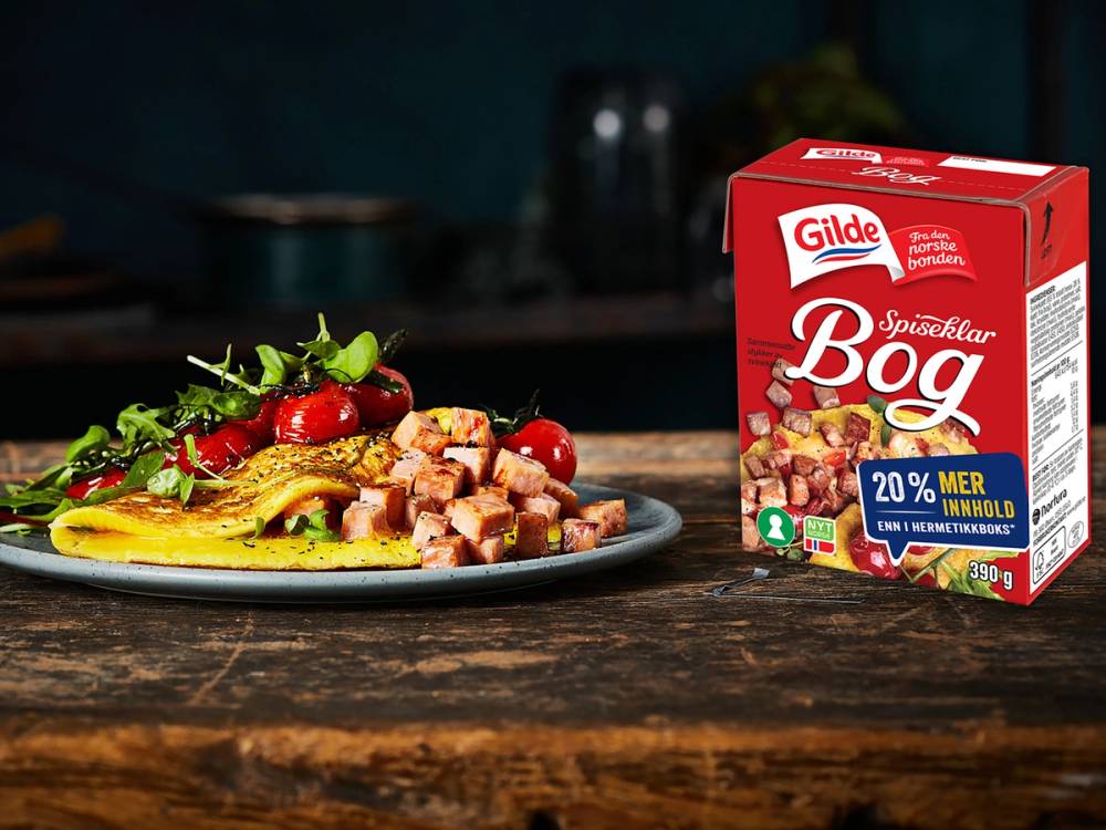 En tallerken med en salat og terninger av Gilde spekepølse ved siden av en pakke Gilde Spekepølses Bag på et kjøkkenbord.