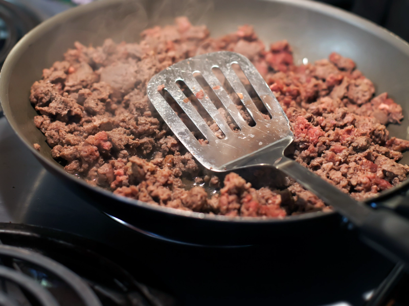 Steker kjøttdeig i en panne med en metallrist, som viser hvordan man kan steke kjøttdeigen riktig.
