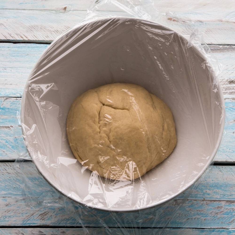 Deigen til fastelavensboller ligger i en bolle dekket med plastfolie, klar til heving.