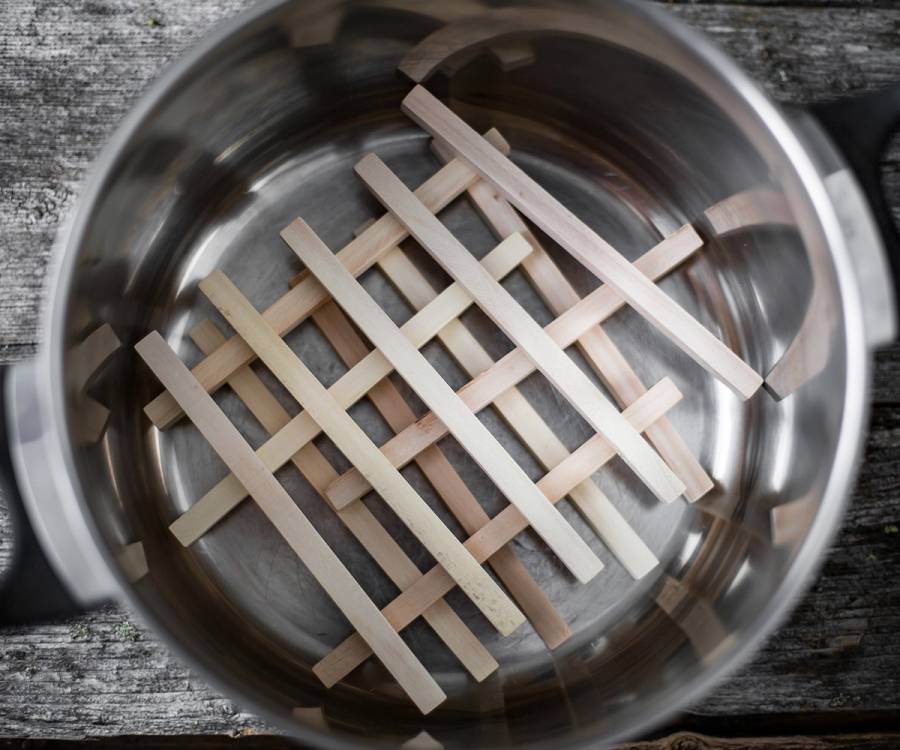 Bilde av flere pinnekjøttpinner laget av bjørkepinner i en metallbolle.