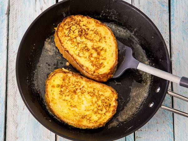 To armeriddere stekes i en panne med smør, med en metallspatel ved siden av, på et lyst bord.