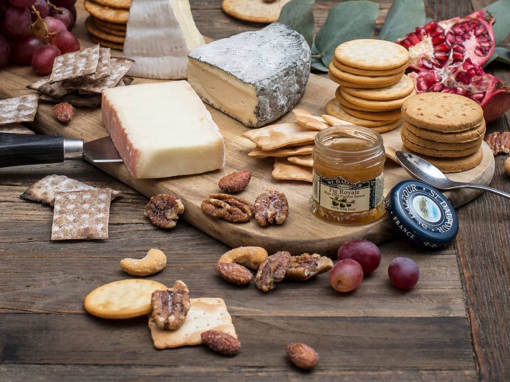 Kjeks og ost på et trebord med ulike typer kjeks, ost, nøtter og druer.