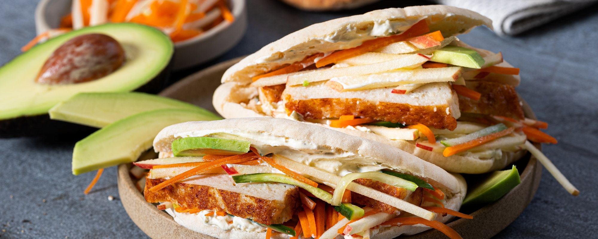 Fiskekaker i pita med grønnsaker og saus, servert på et fat.