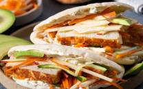 Fiskekaker i pita med grønnsaker og saus, servert på et fat.