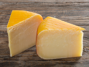 To stykker ost med gul og hvit farge på en treplate.