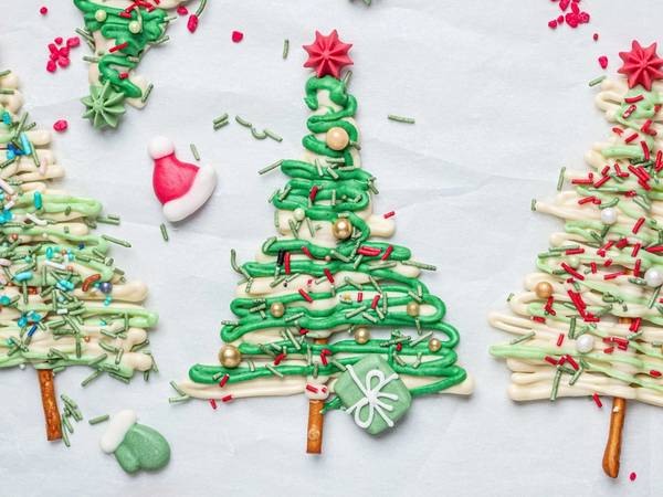 Små juletrær laget av sjokolade med pynt og dekorasjoner på en hvit bakgrunn