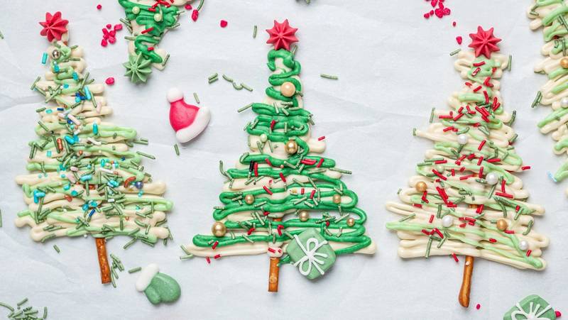 Små juletrær laget av sjokolade med pynt og dekorasjoner på en hvit bakgrunn