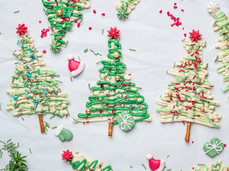 Små juletrær laget av sjokolade med pynt og dekorasjoner på en hvit bakgrunn