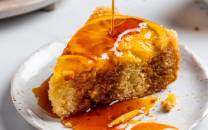 En opp ned appelsinkake med glasur som drypper ned på en hvit tallerken