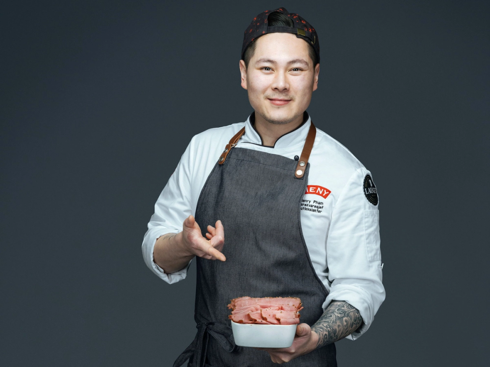 Person i kokkeantrekk peker på en form med nyskåret pastrami av norsk Angus