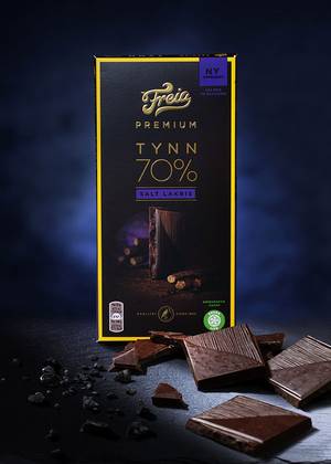 Pakke med Freia Premium salt lakris med noen bruttede lakrisstykker foran, mot en mørk bakgrunn.