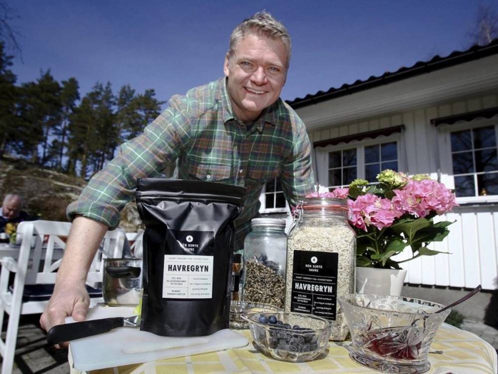 Person som står på en terrasse med ulike poser og beholdere med havregryn og blomster i bakgrunnen.