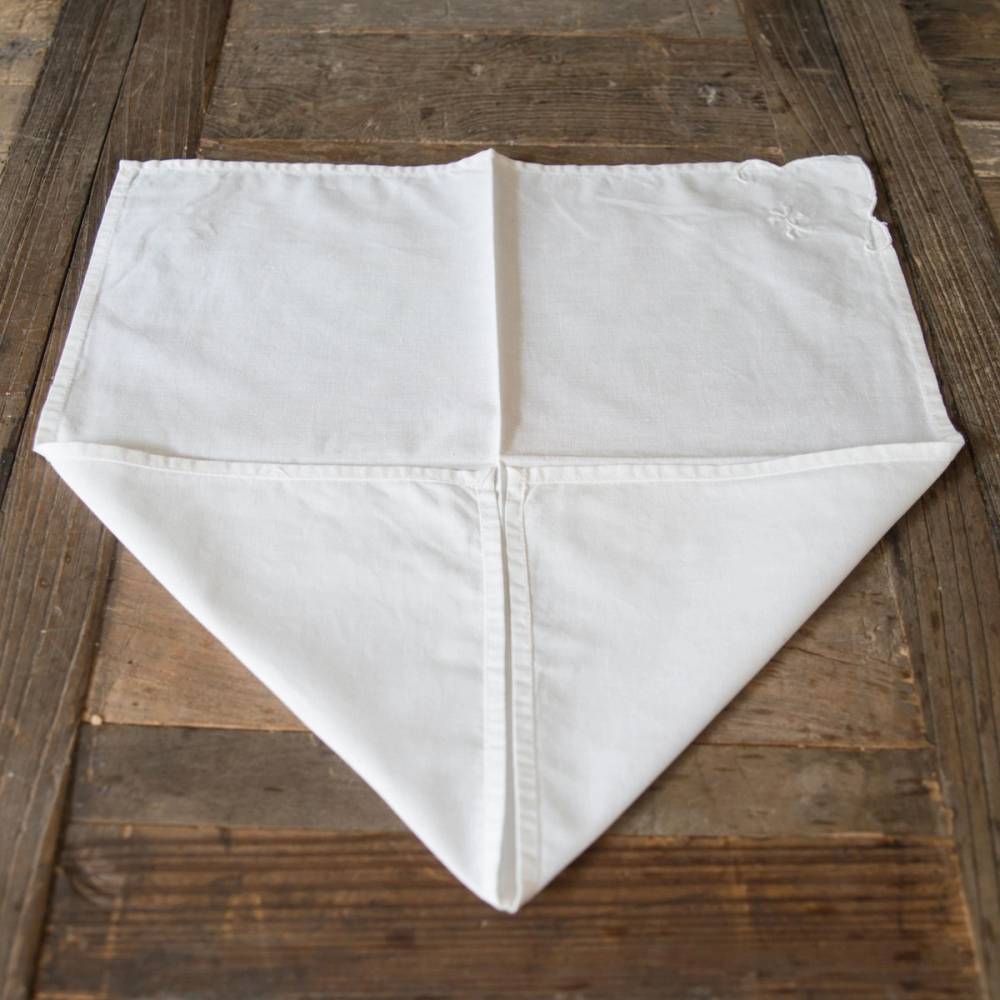 En hvit serviett brettet i en trekant, lagt på en trebenke.