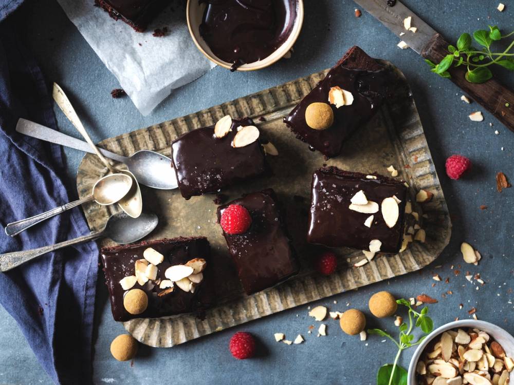 Langpannekaker med blank glasur pyntet med mandler og bringebær på et fat.