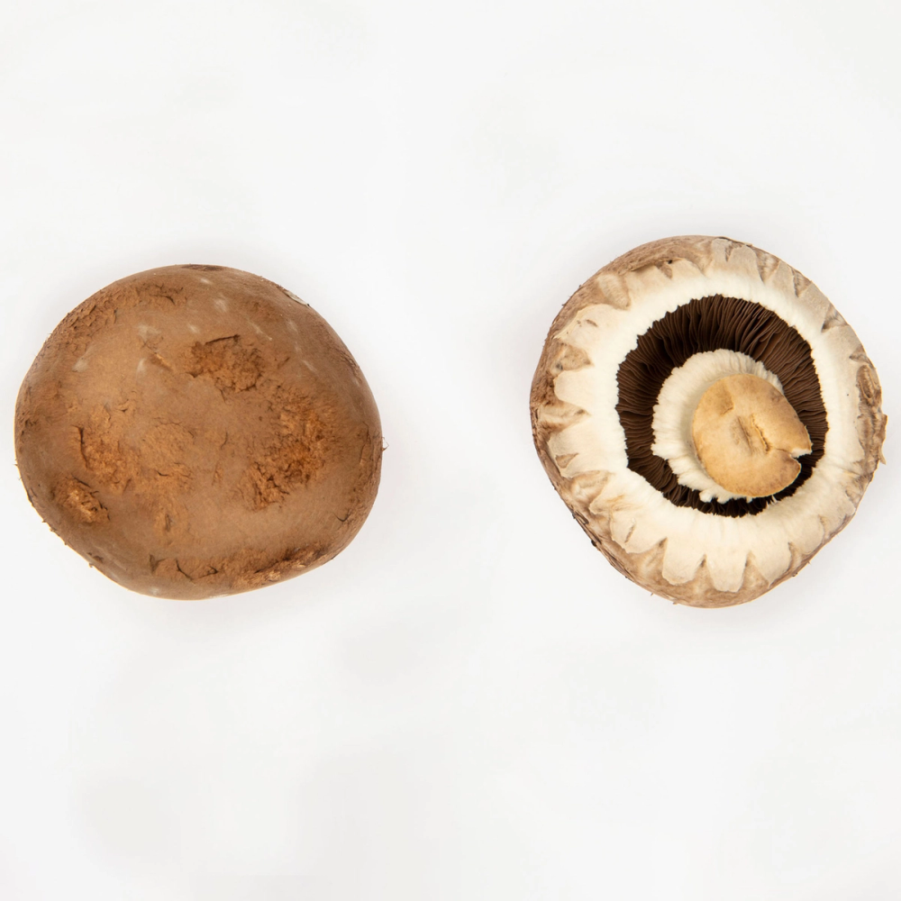 En hel og en skåret aromasopp viser den brune utsiden og den hvite innsiden med mørke skiver.