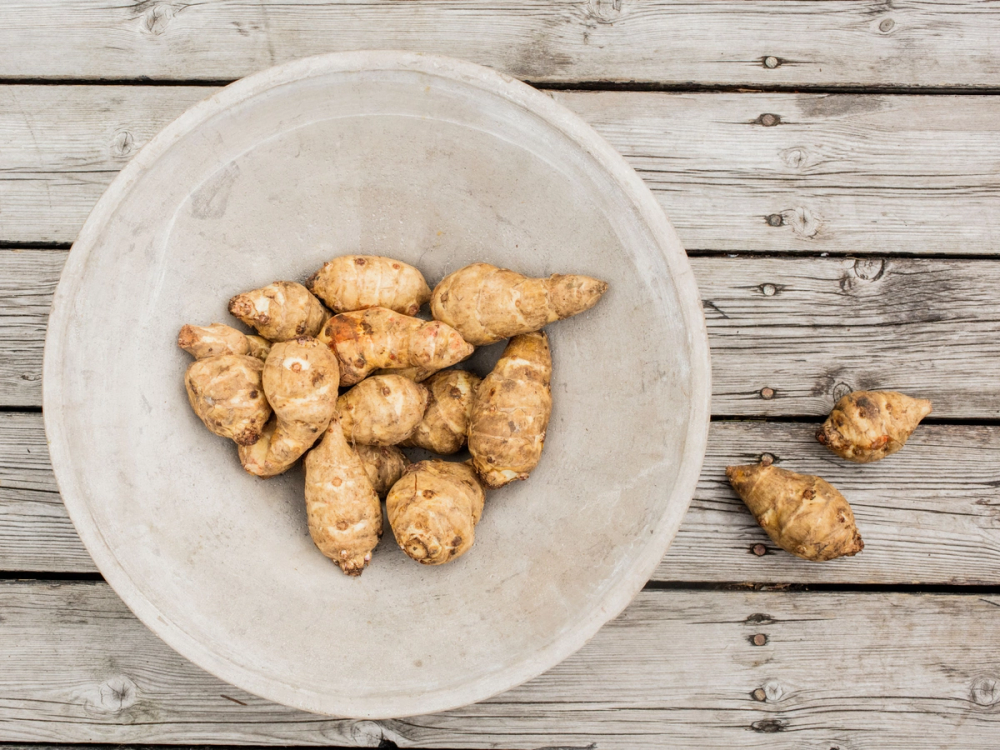 Jordskokk som ligger i en hvit skål på et treverkbord