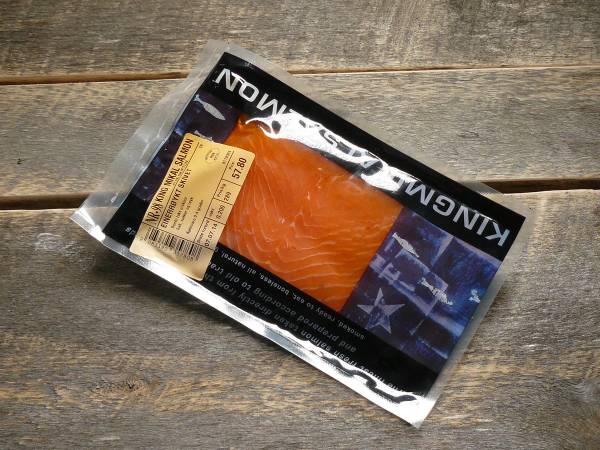 Pakke med fersk laksefilet på en treoverflate, merket med Mikals-laks.