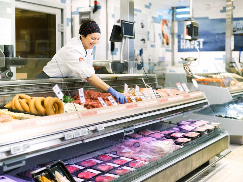 Kjøtt- og fiskedisk i en dagligvarebutikk med ansatte som håndterer varene.