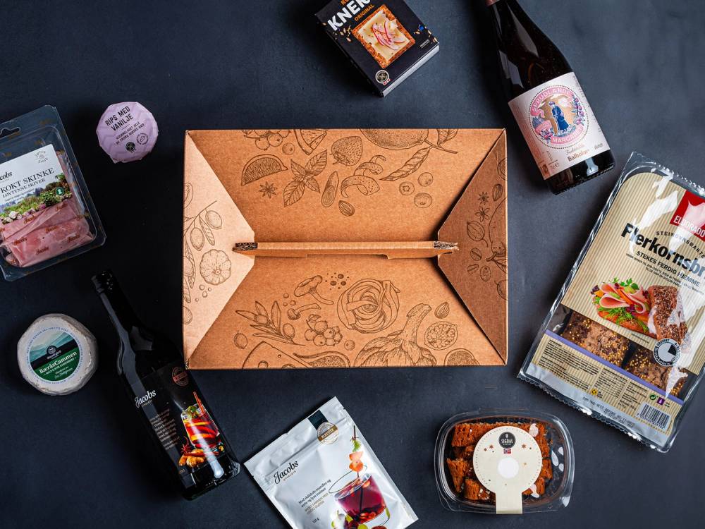En åpen matgaveeske med ulike matvarer og små gaver rundt på en mørk bakgrunn.