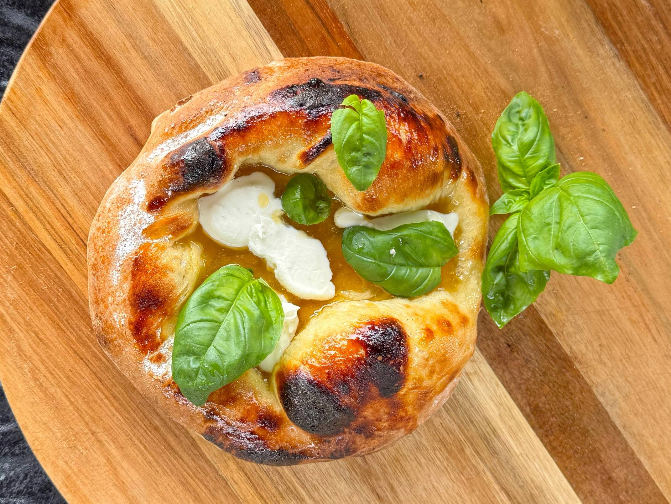 En pizza med ost og friske basilikumblader på en treplate.