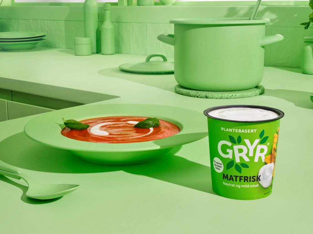 En grønn kjøkkenbenk med en grønn gryte og en grønn matfisk-skje, samt en kopp og en pakke med Gryr plantebasert matfisk, alt i grønntone.