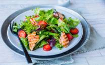 En frisk salat med grønne blader, asparges, skiveskåret laks og jordbær.