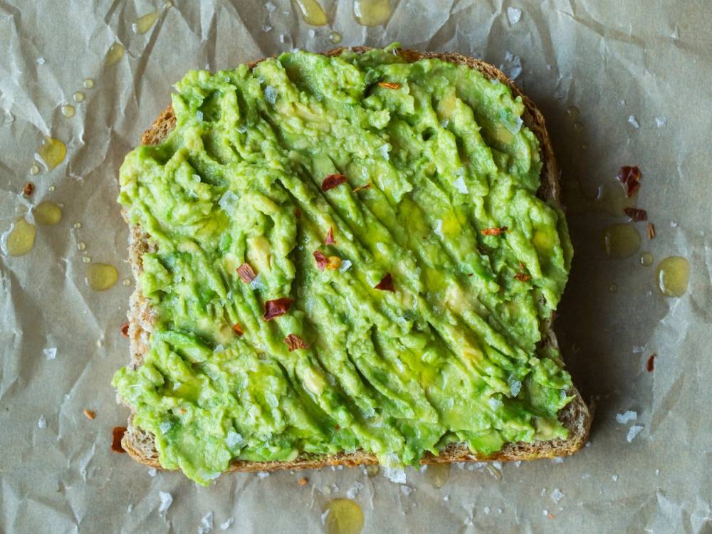Brødskive med most avokado og små biter av rød chili på toppen