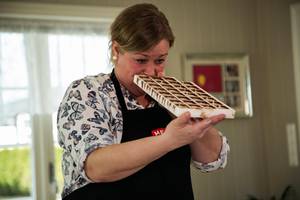 Person som undersøker en sjokoladekari i et kjøkken med vindu og hyller i bakgrunnen