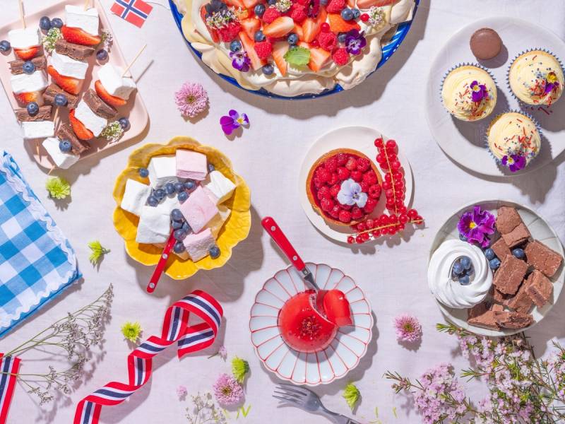 Et utvalg av kaker, cupcakes og godteri på et sommerlig dessertbord med blomster og dekorasjoner.