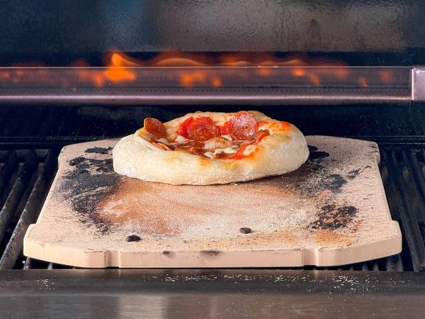 Pizza med tomatsaus og bacon stekes i en ovn på en stekeplate.