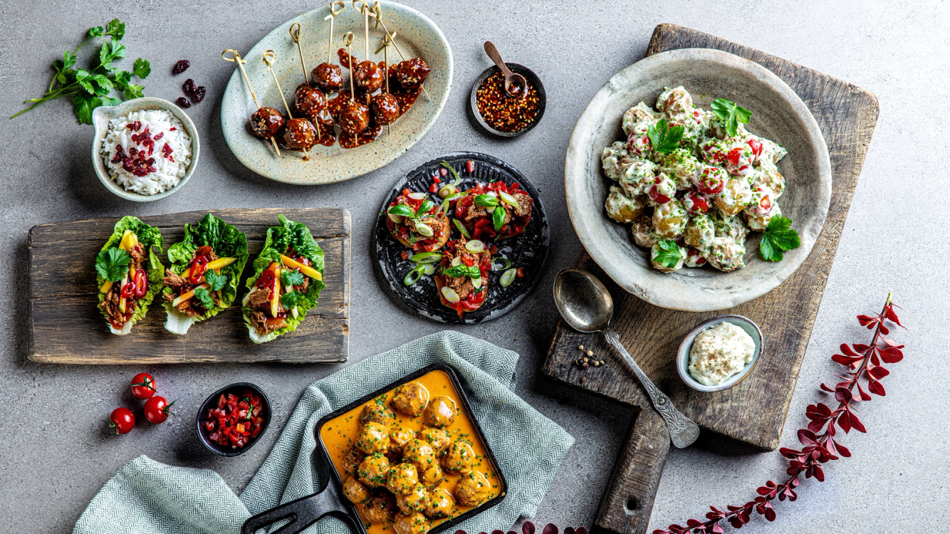 Et utvalg vegetar-tapas på ulike tallerkener og fat, inkludert salater, småretter og dipper, på et bord med dekorative elementer.