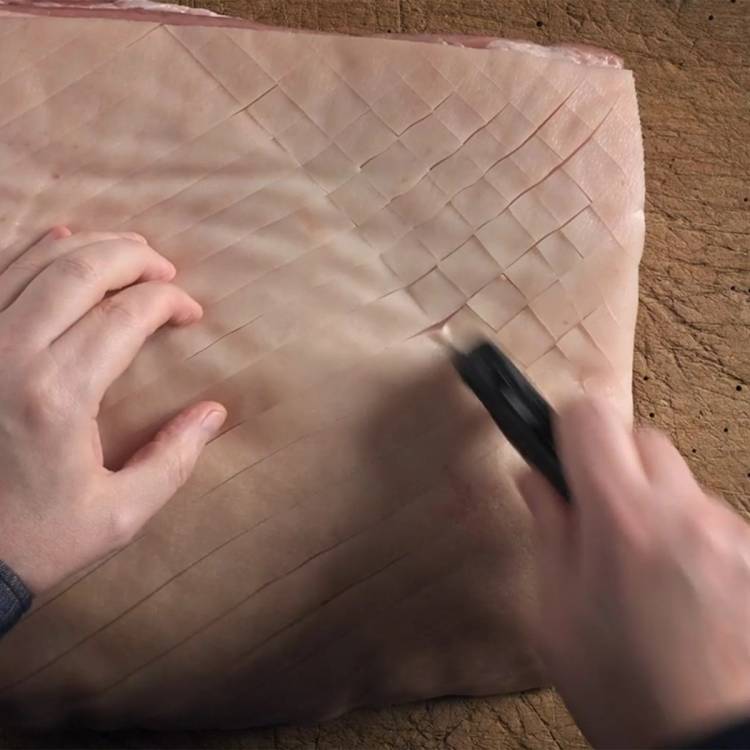 En person bruker en svart penn til å lage et rutemønster på et stykke rosa eller beige lær eller stoff.