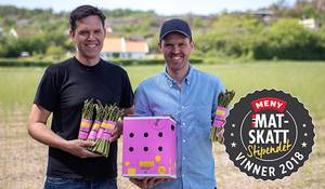 To personer som holder matprodukter og en eske, med en logo for MatSkatt og teksten 'Vinner 2018' i bakgrunnen.