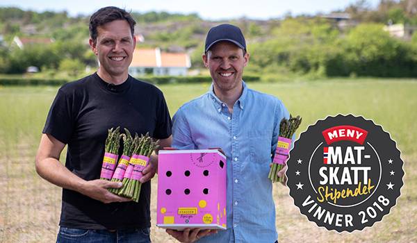 To personer som holder matprodukter og en eske, med en logo for MatSkatt og teksten 'Vinner 2018' i bakgrunnen.