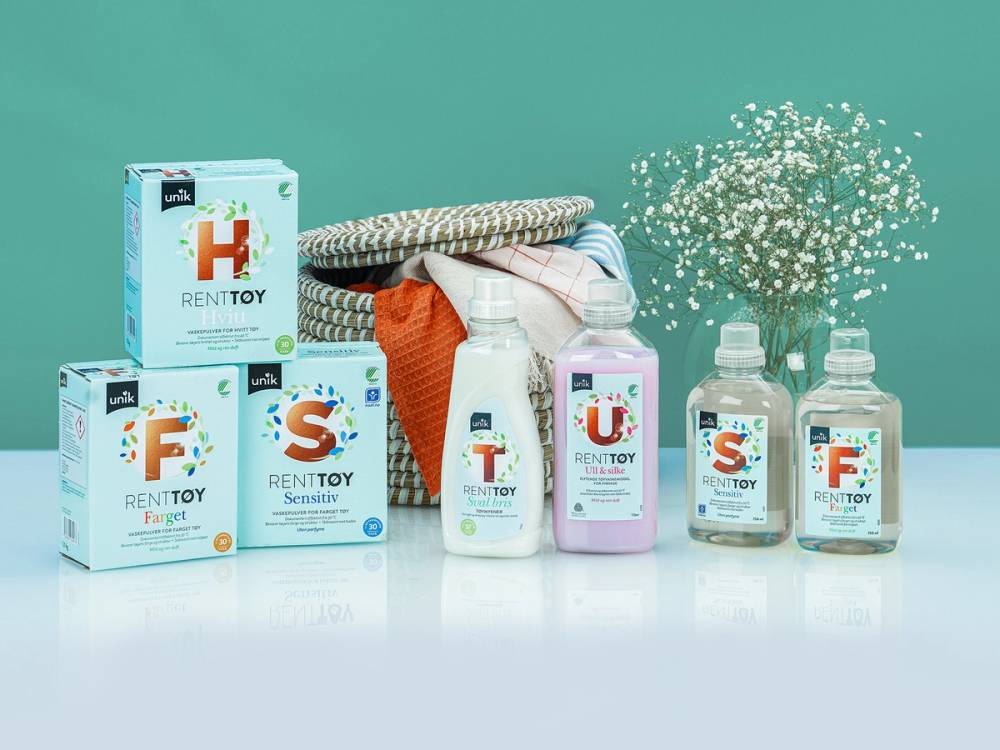 En samling med rengjøringsprodukter og et brett med tøy, med en grønn bakgrunn, som antyder rent tøy og rengjøring.