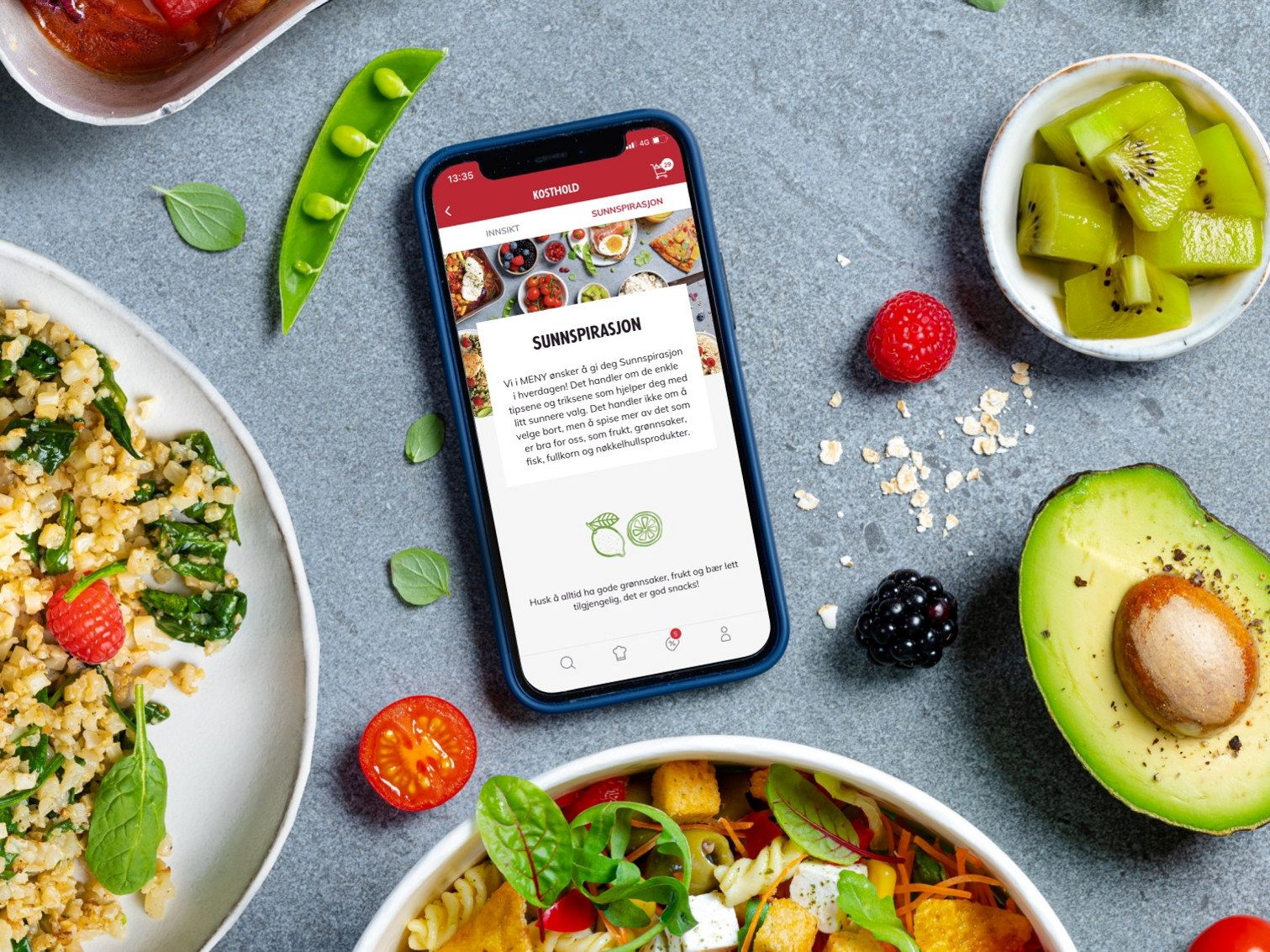 En mobiltelefon som viser en nettside om sunnspirasjon, omgitt av frukt og grønnsaker på en bordflate.