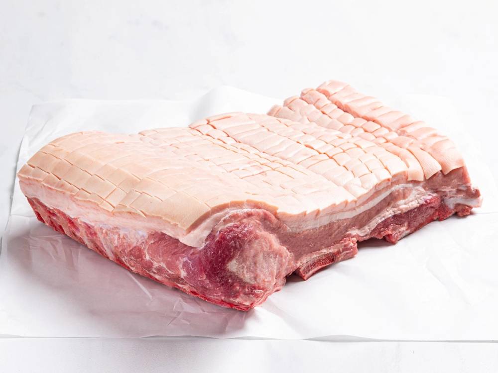 Et stykke med svinefett og kjøtt, sannsynligvis ribbe, på en hvit bakgrunn.