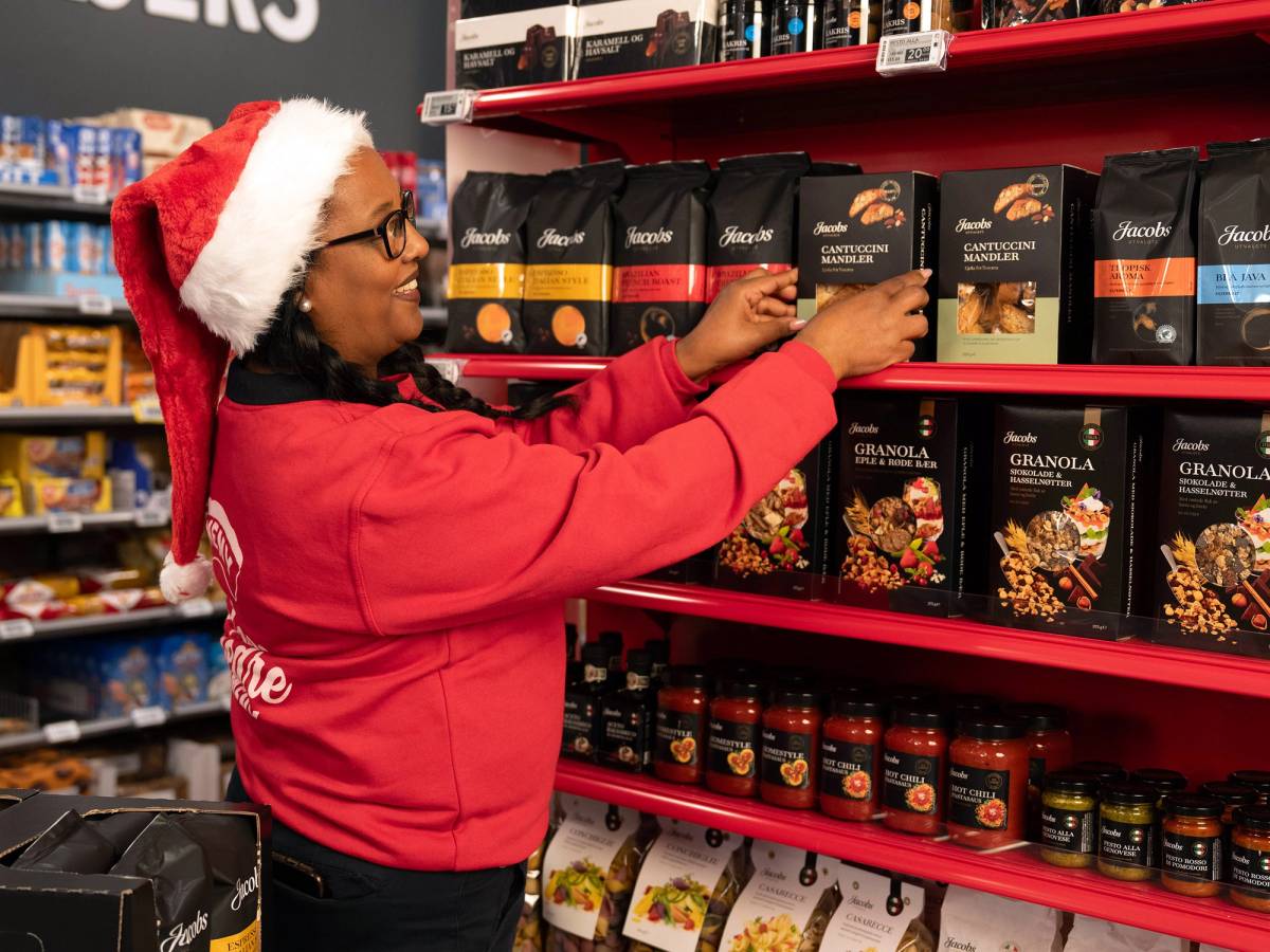 En ansatt plasserer Jacobs utvalgte produkter på en hylle i en butikk i julen 2023.