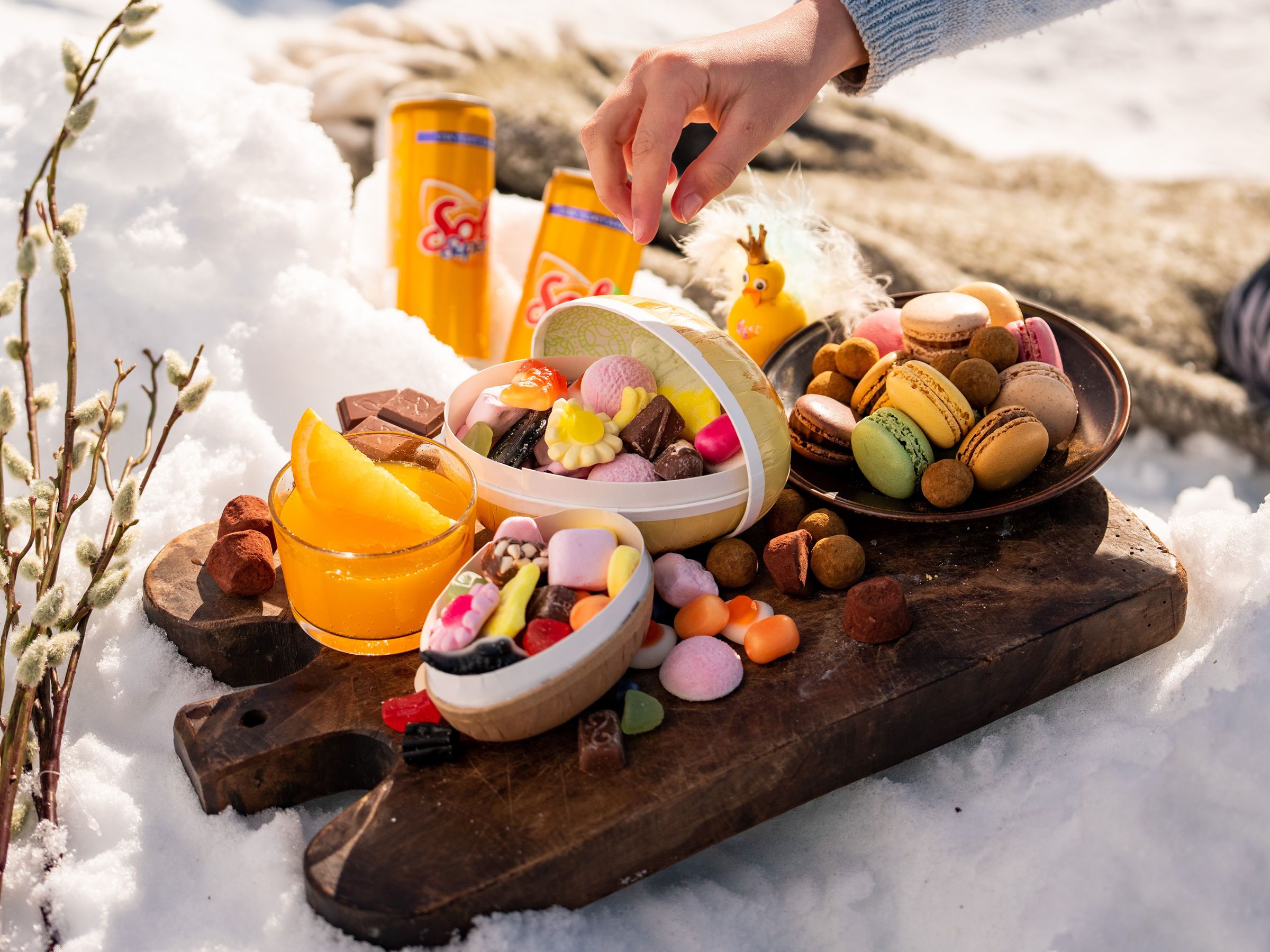 Påskegodt og påskeegg på et trebrett ute i snøen.